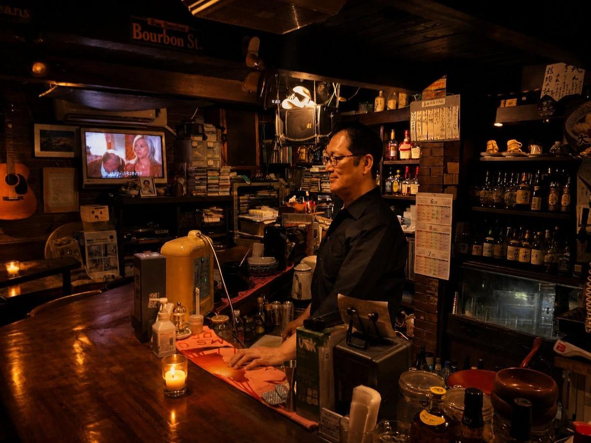 灯りのともるカウンターに立つ店主